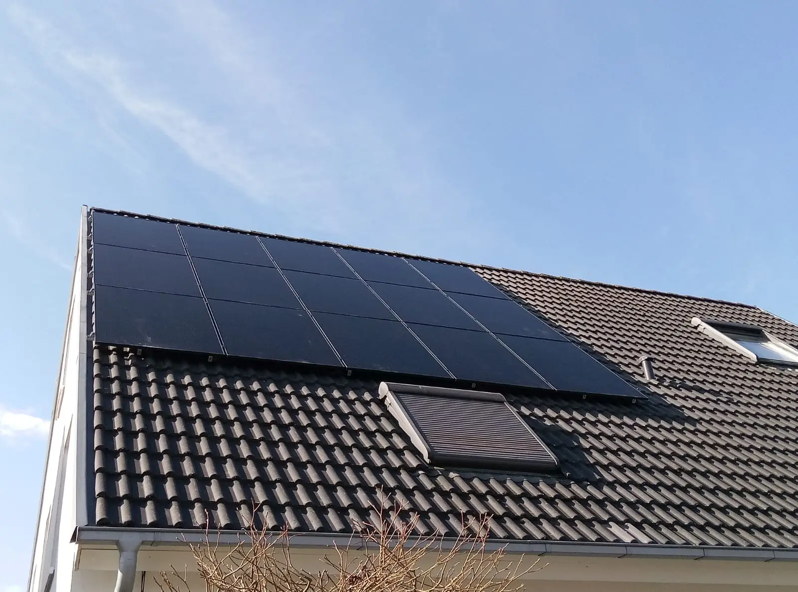 Schwarze Solarmodule auf einem Ziegeldach mit Dachfenster